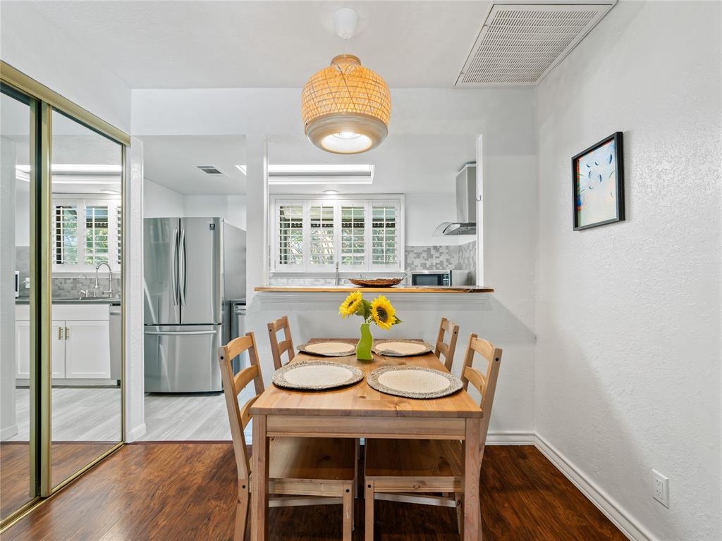 Wood-finish flooring, built-in shelving, stainless steel appliances, and white cabinetry Wood-finish flooring, built-in shelving, stainless steel appliances, and white cabinetry