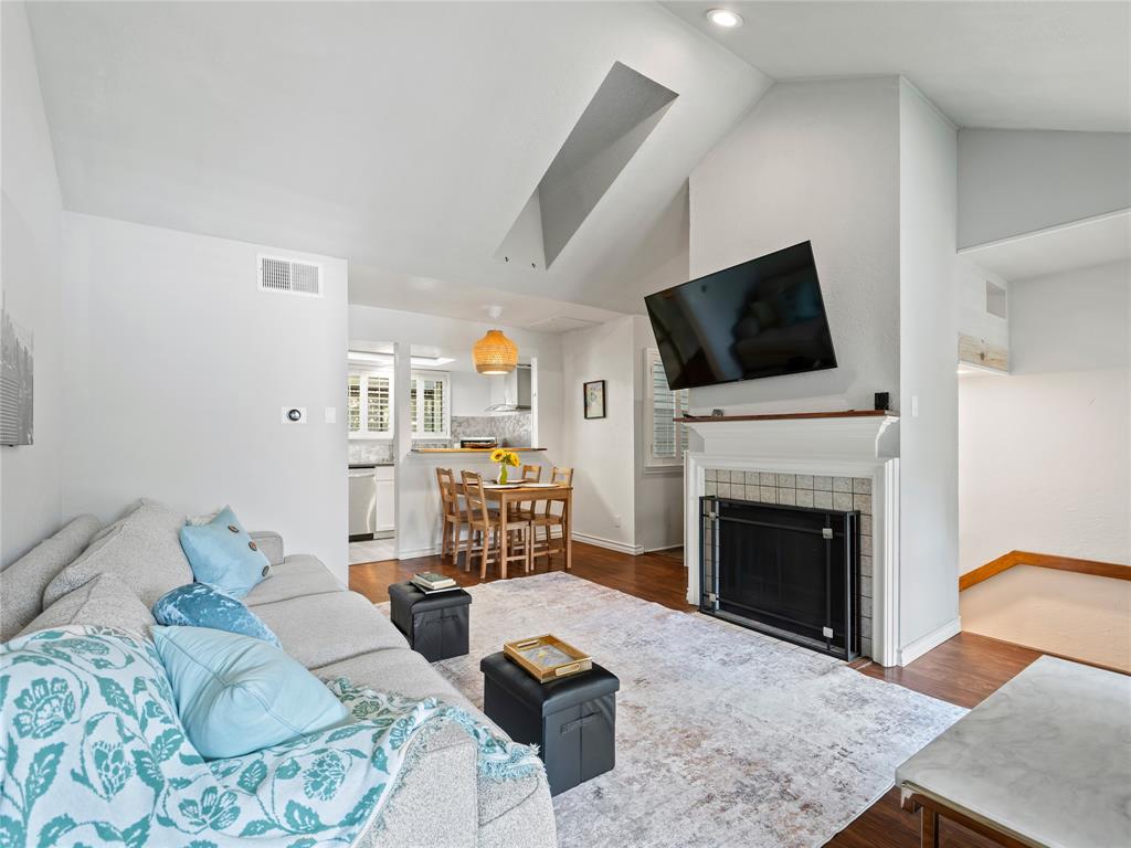 Vaulted ceiling, recessed lighting, wood-finish flooring, fireplace with tile surround, kitchen with white appliances Vaulted ceiling, recessed lighting, wood-finish flooring, fireplace with tile surround, kitchen with white appliances