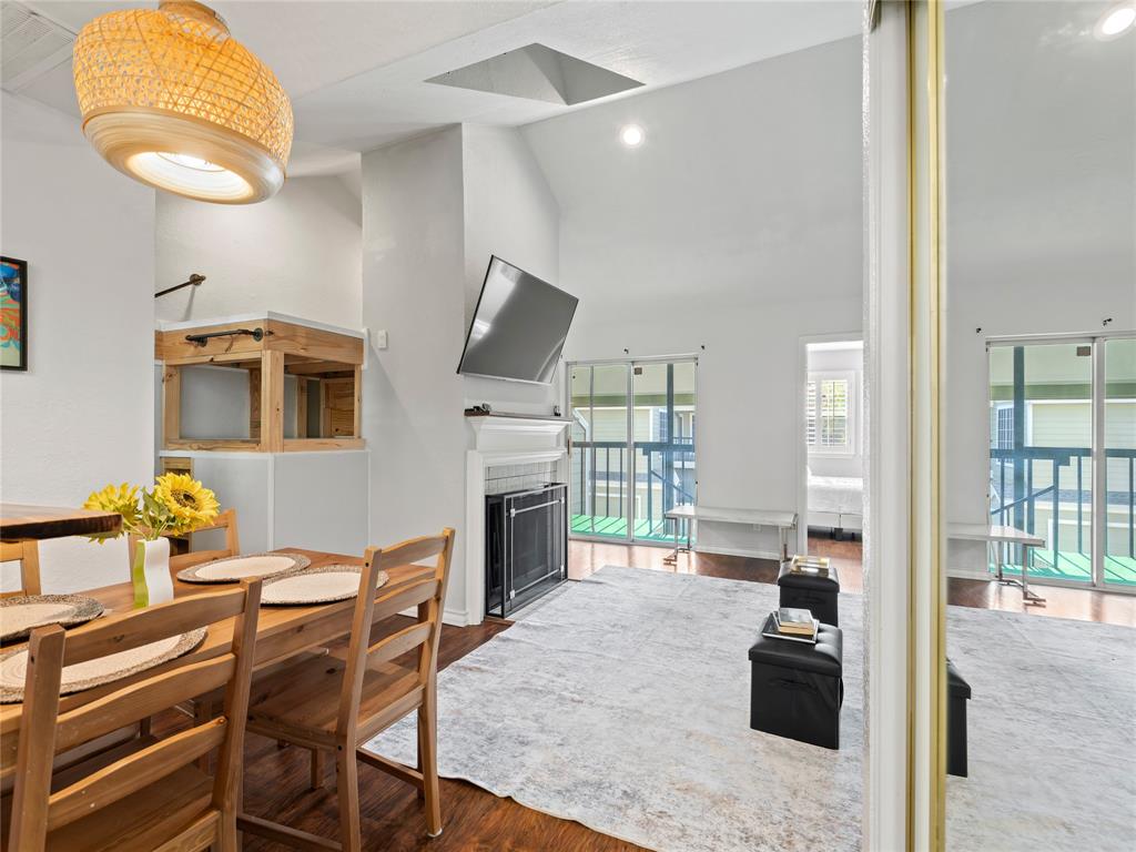 Vaulted ceiling, wood-finish flooring, built-in fireplace, sliding glass doors, and a decorative light fixture Vaulted ceiling, wood-finish flooring, built-in fireplace, sliding glass doors, and a decorative light fixture
