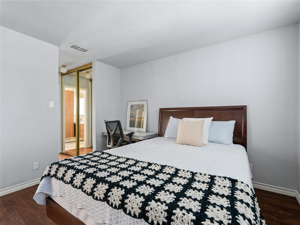 Wood-finish flooring with light-colored walls and a gold-framed mirrored closet Wood-finish flooring with light-colored walls and a gold-framed mirrored closet