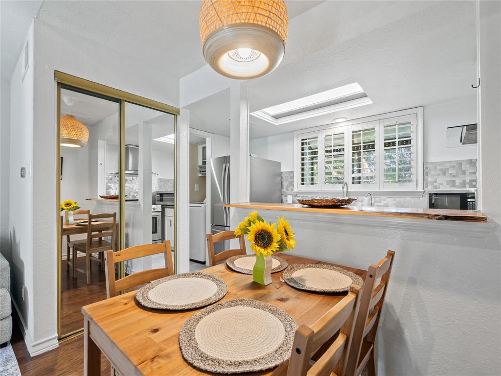 Dining area with wood-finish flooring, a woven pendant light fixture, and mirrored closet doors Dining area with wood-finish flooring, a woven pendant light fixture, and mirrored closet doors