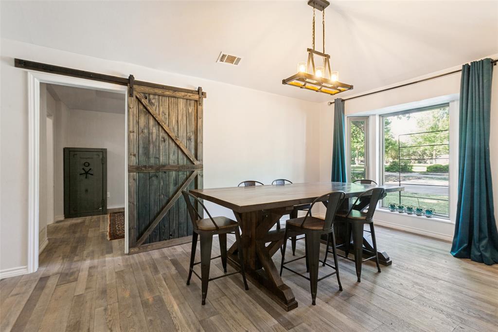 Wood-finish flooring, a wood barn door, and an overhead chandelier with exposed bulbs