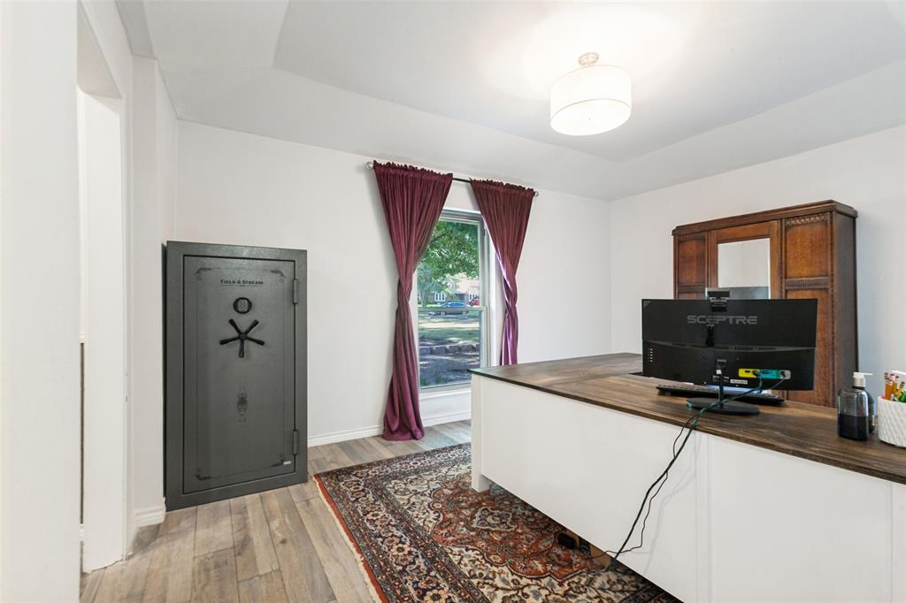 Tray ceiling, wood-finish flooring, built-in desk with wood-finish top, drum pendant light fixture, window with exterior landscaping