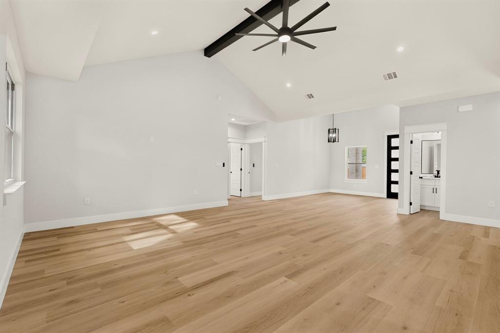 Vaulted ceiling with an exposed beam, wood-finish flooring, recessed lighting, modern ceiling fan, and a contemporary pendant light fixture
