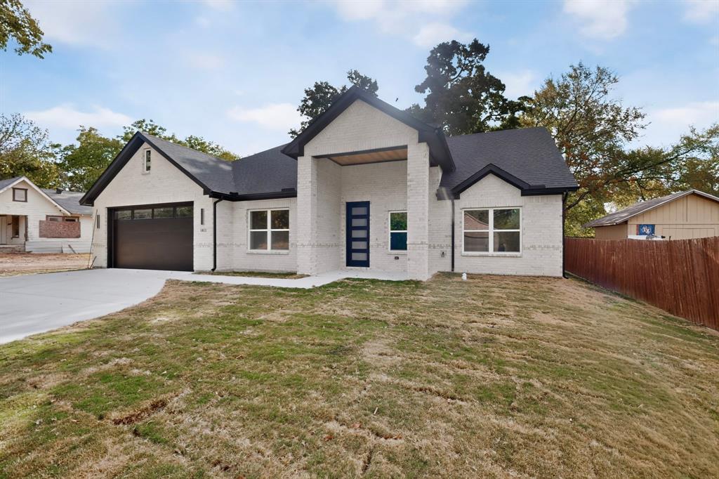 Modern architecture featuring a two-car garage, white brick exterior, black trim, and a contemporary entry door