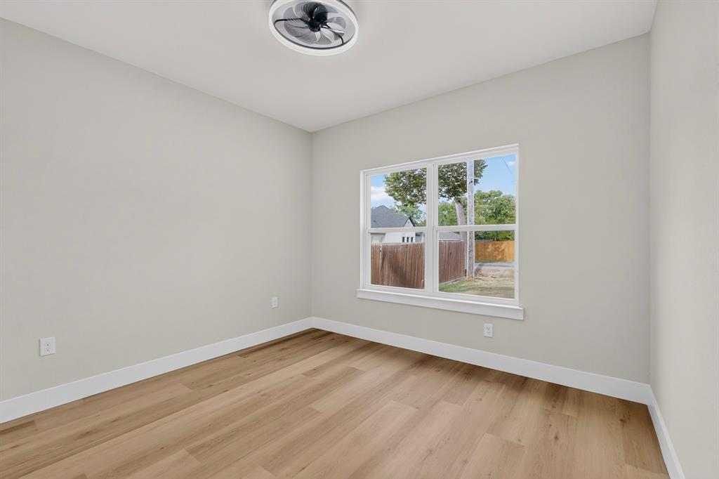 Recessed ceiling light with fan, wood-finish flooring, white walls, and a large window