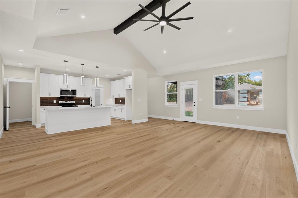Spacious living area featuring wood-finish flooring and a vaulted ceiling with a modern ceiling fan