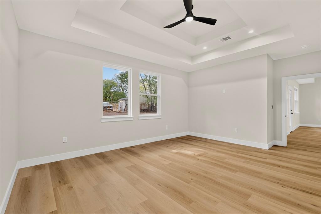 Expansive interior featuring wood-finish flooring, a tray ceiling, and a modern ceiling fan