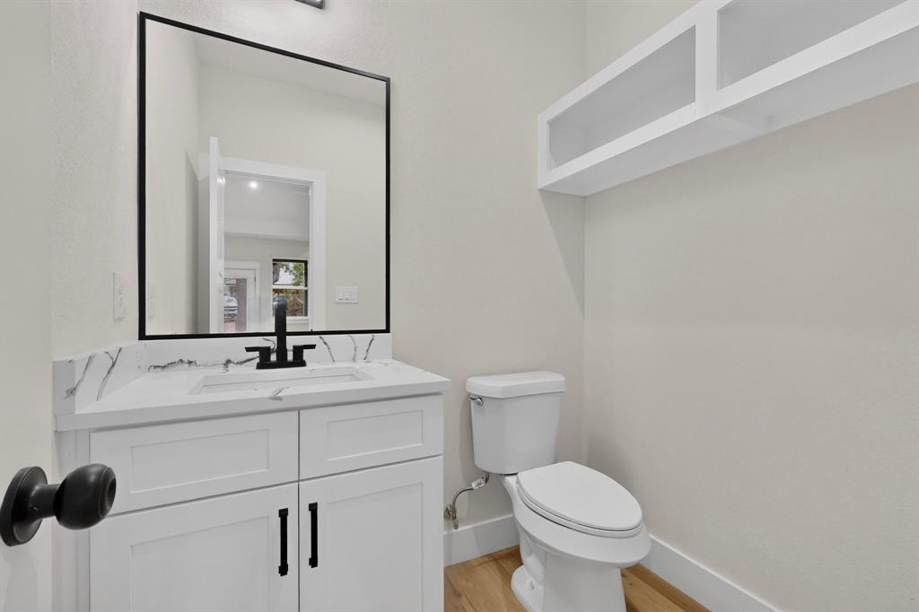 White vanity with a stone-finish countertop, undermount sink, and black wall-mounted faucet