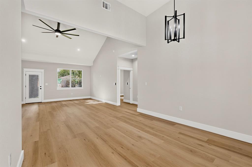 Vaulted ceilings, wood-finish flooring, modern ceiling fan, contemporary light fixture, and white trim throughout