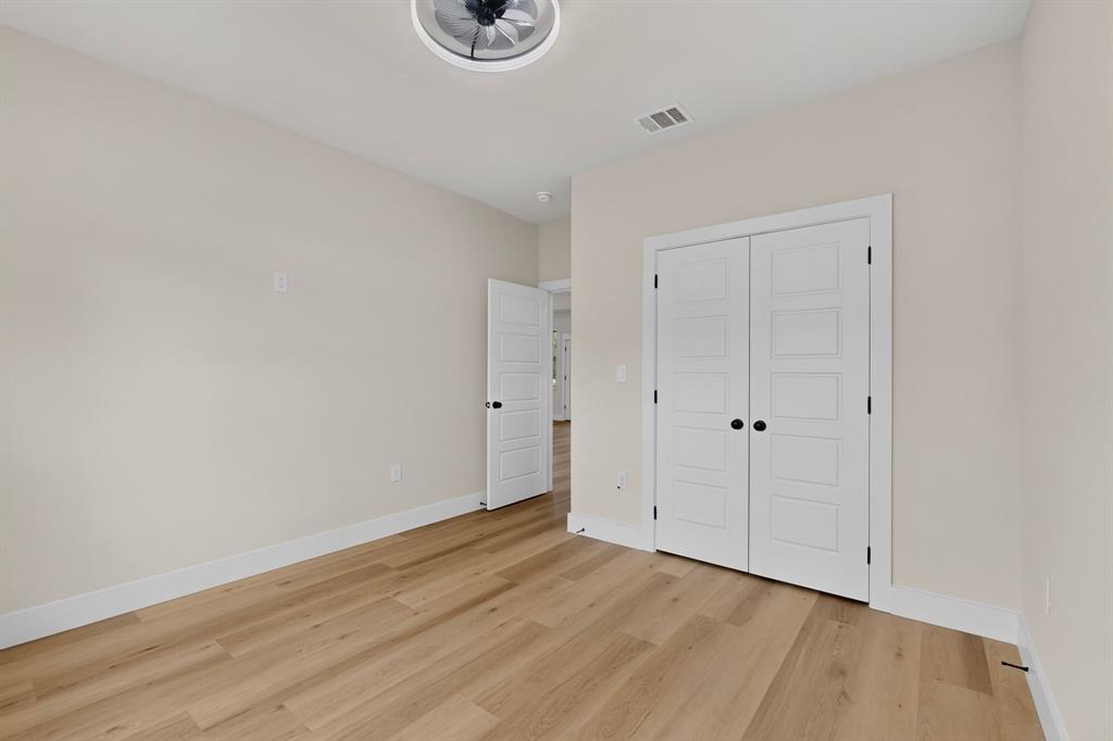 Wood-finish flooring throughout, bright white trim, and a modern ceiling fan with integrated lighting