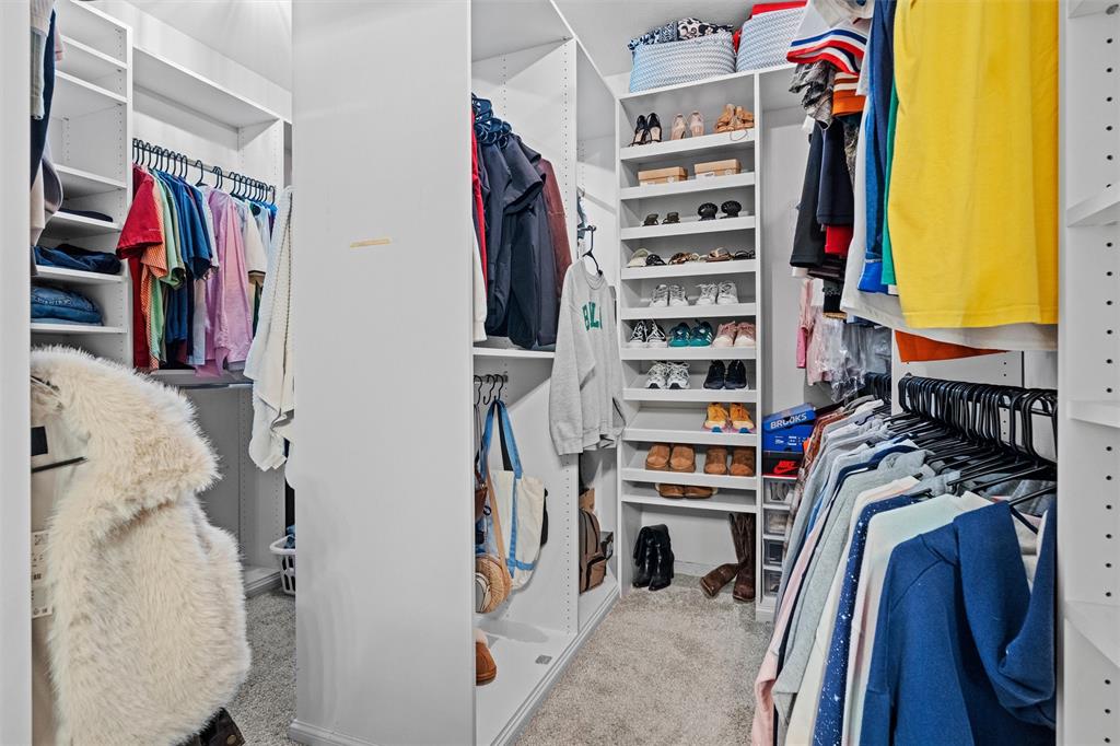 Oversized walk in closet with custom organization system, abundant storage and dedicated shoe shelving.