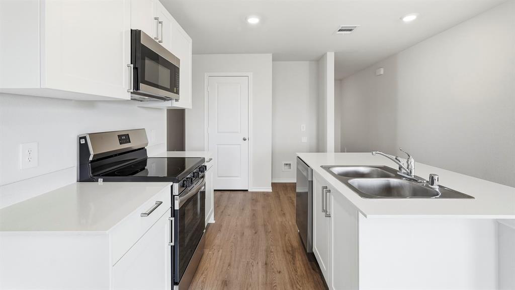 Bright kitchen featuring white cabinetry, stainless steel appliances, wood-finish flooring, white countertops, and recessed lighting Bright kitchen featuring white cabinetry, stainless steel appliances, wood-finish flooring, white countertops, and recessed lighting