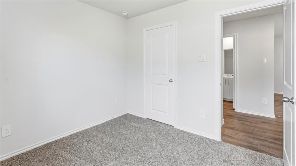 Neutral tone walls, grey carpet flooring, white trim, recessed lighting, and a white interior door