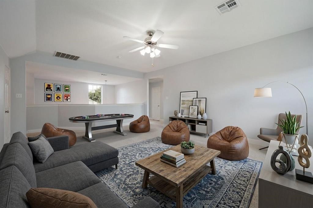 Open-concept living area with a ceiling fan, light-toned walls, and soft carpeting