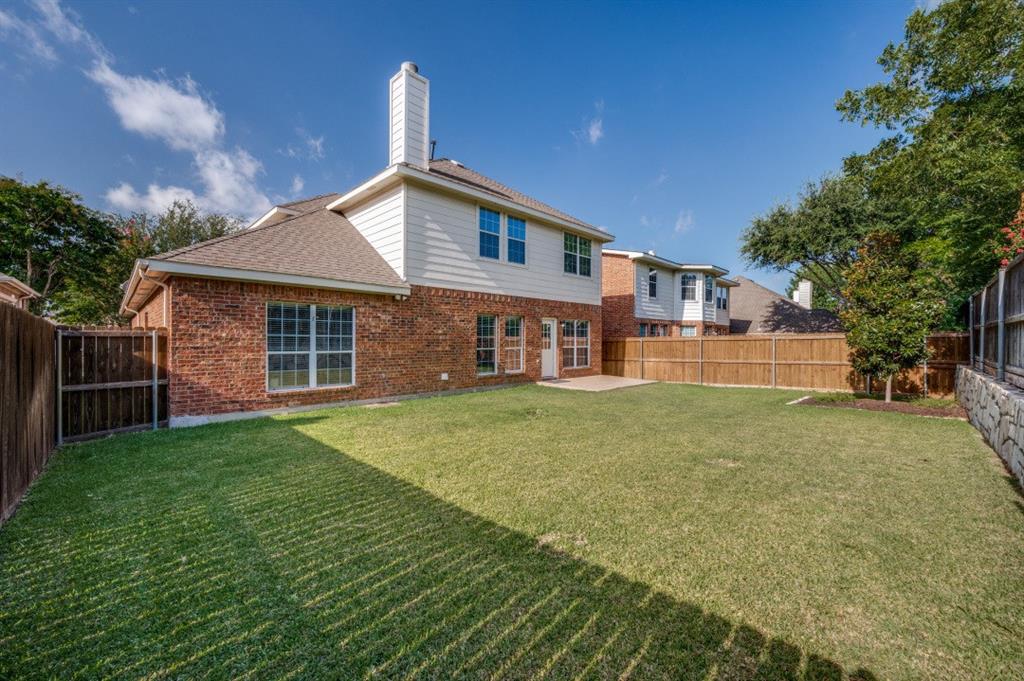 Expansive backyard with a manicured lawn, brick exterior, and a privacy fence