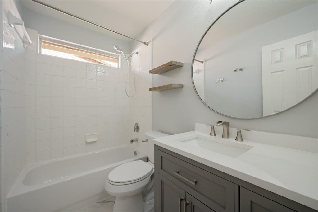 Full bathtub with white tile surround and overhead window