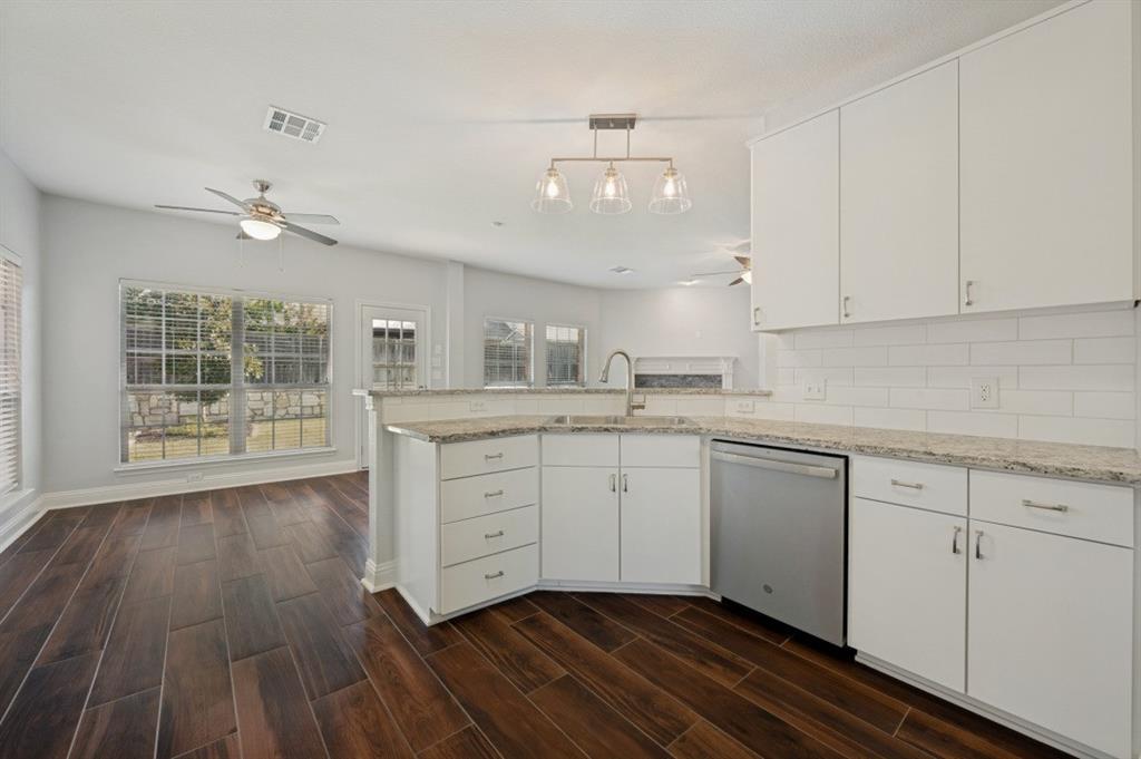 Kitchen with white cabinetry, stainless steel dishwasher, white subway tile backsplash, and light-toned countertops