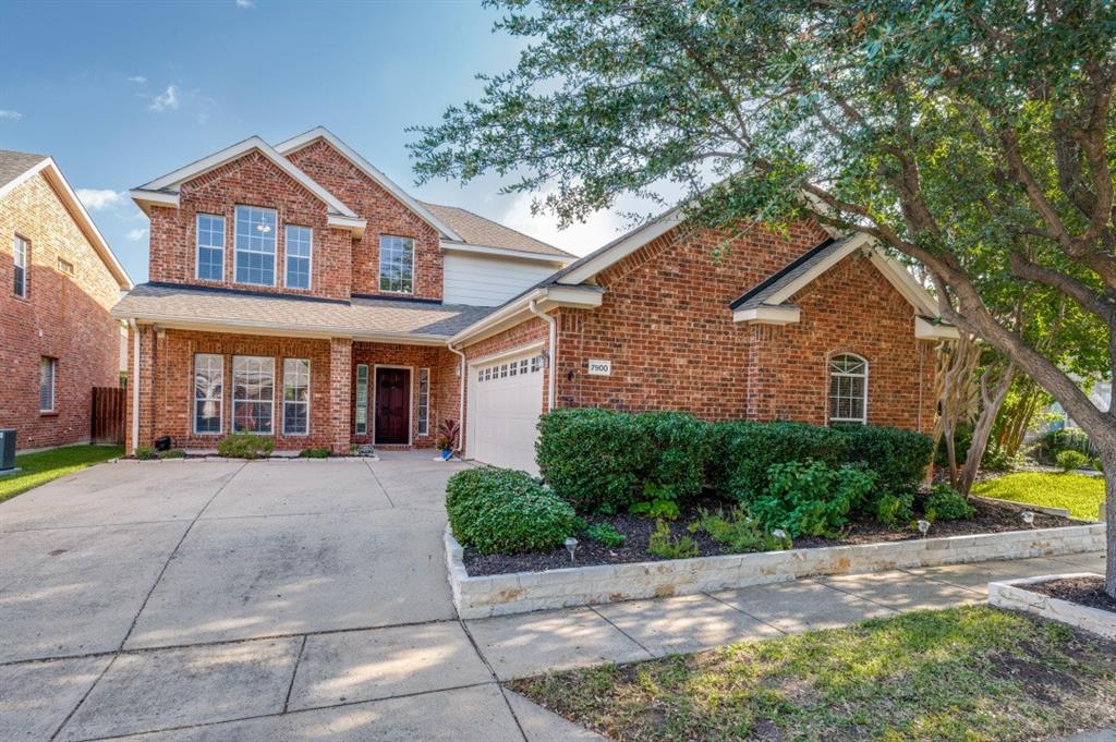 Brick exterior with a gabled roofline, columned entryway, attached garage, and landscaped front garden