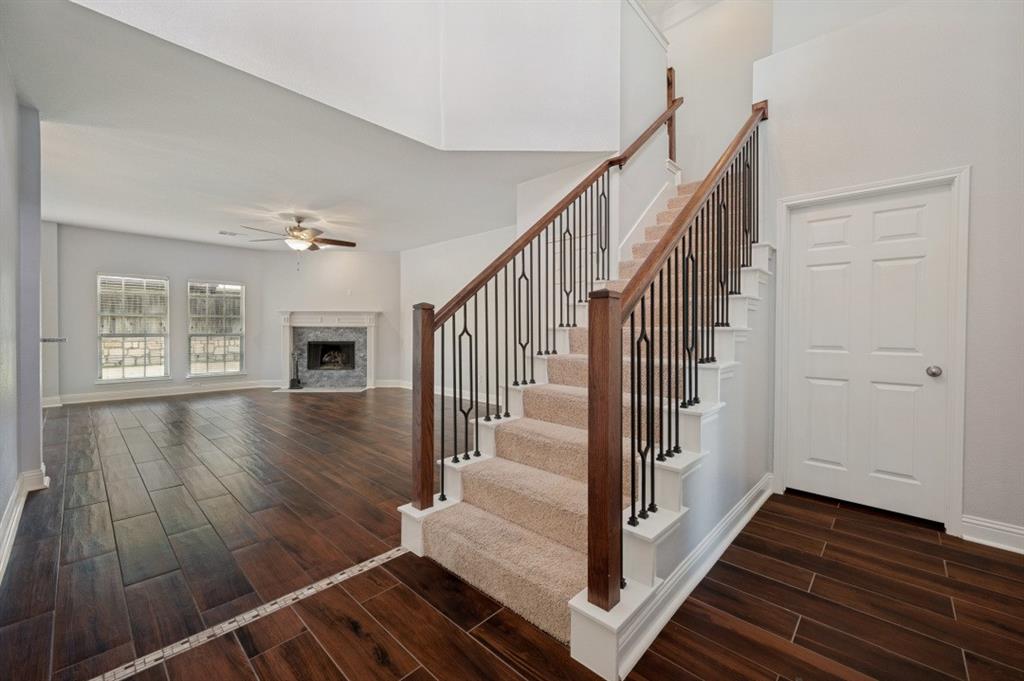Expansive living area with wood-finish flooring, a ceiling fan, and a fireplace with a light-colored mantel