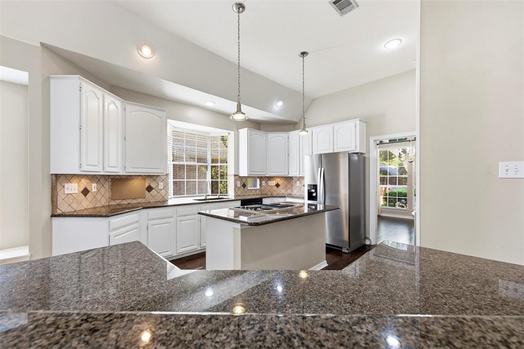 Kitchen featuring white cabinetry, granite countertops, tile backsplash, and stainless steel appliances