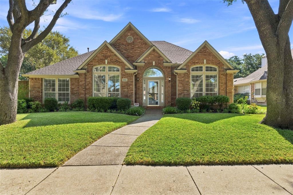 Elegant brick Colonial estate showcasing arched entryways, multi-pane windows with decorative pediments, and a welcoming covered entry portico Elegant brick Colonial estate showcasing arched entryways, multi-pane windows with decorative pediments, and a welcoming covered entry portico