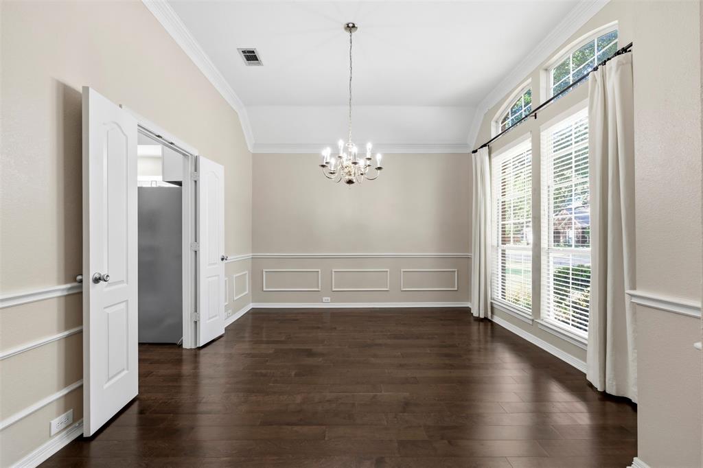 Vaulted ceiling, dark wood-finish flooring, decorative wall molding, arched transom windows, and a multi-arm chandelier Vaulted ceiling, dark wood-finish flooring, decorative wall molding, arched transom windows, and a multi-arm chandelier