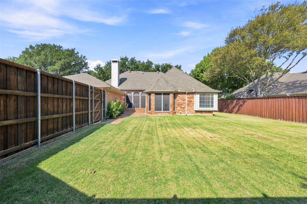 Expansive backyard featuring a manicured lawn, brick exterior, bay window, and privacy fencing