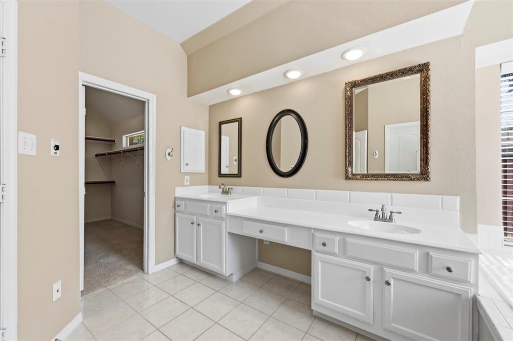 Dual sink vanity with white cabinetry, recessed lighting, and tiled flooring