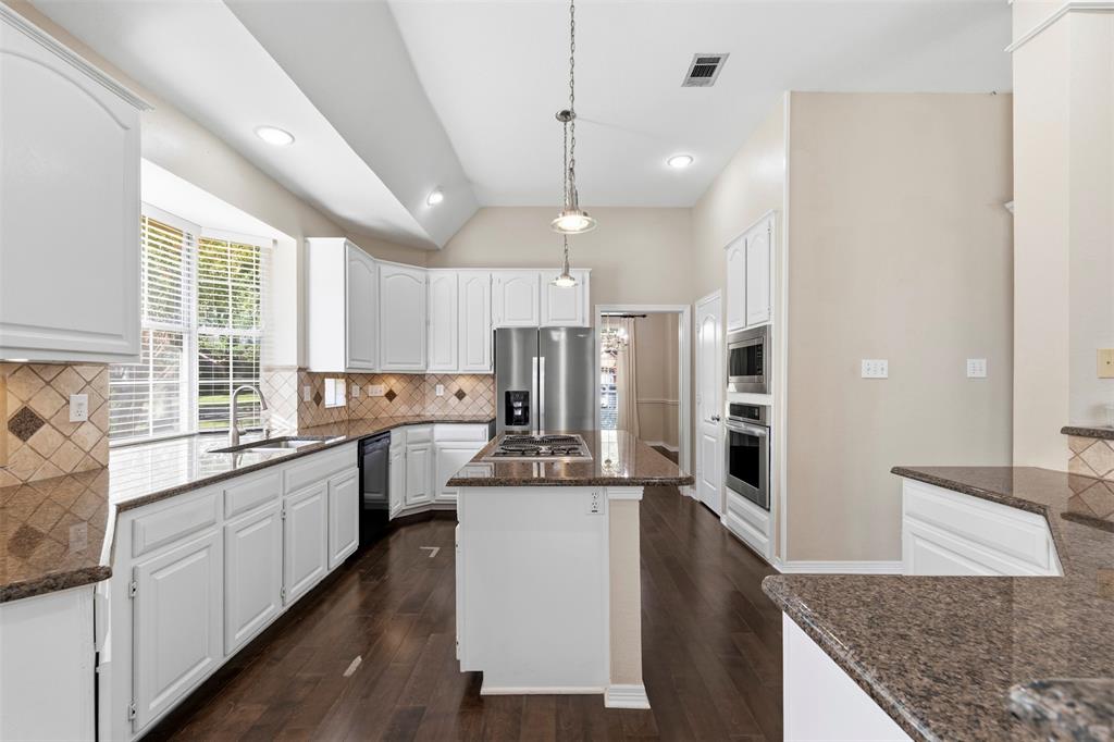 Kitchen featuring white cabinetry, dark wood-finish flooring, granite countertops, and stainless steel built-in appliances