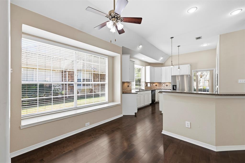 Vaulted ceilings, recessed lighting, and a ceiling fan enhance the open-concept design
