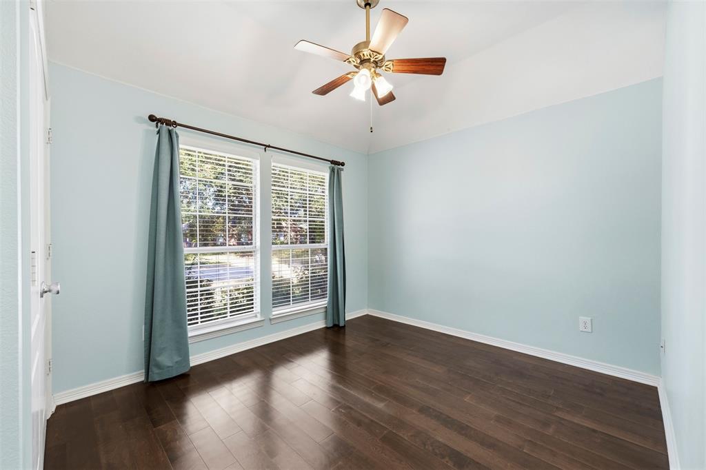 Wood-finish flooring, dual windows with blinds, ceiling fan with integrated lighting, and light blue wall finish