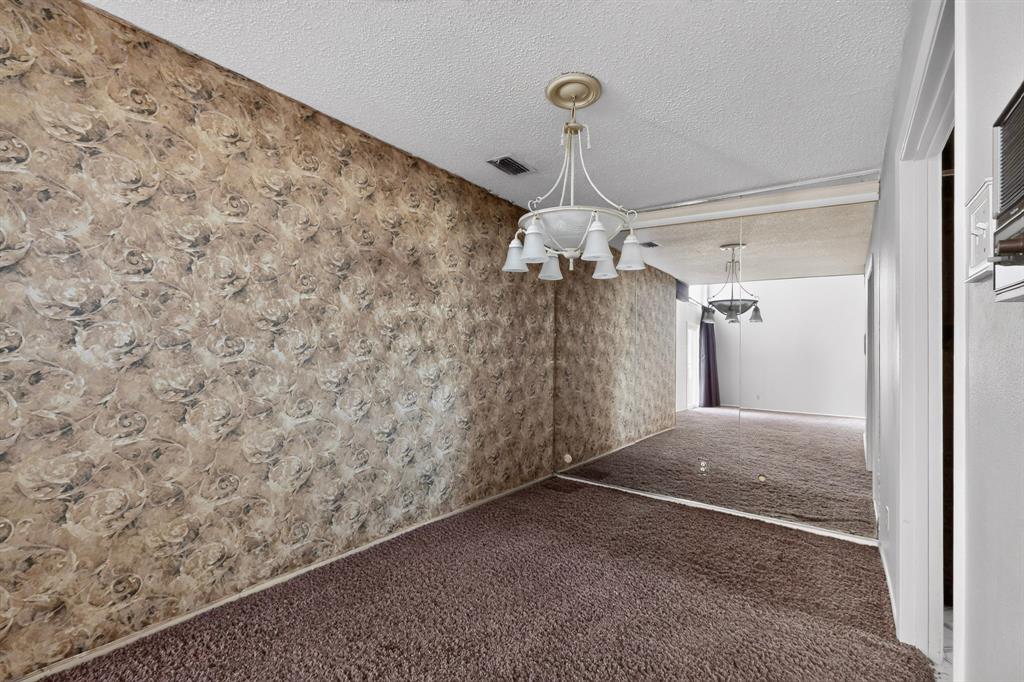 Wallpapered wall, carpeted flooring, mirrored wall, and overhead chandelier