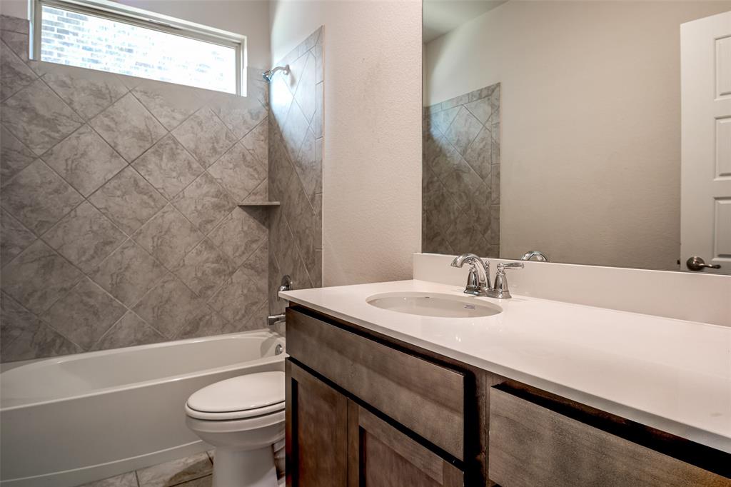Bathroom featuring a wood-finish vanity with a white countertop, an undermount sink, and a chrome faucet