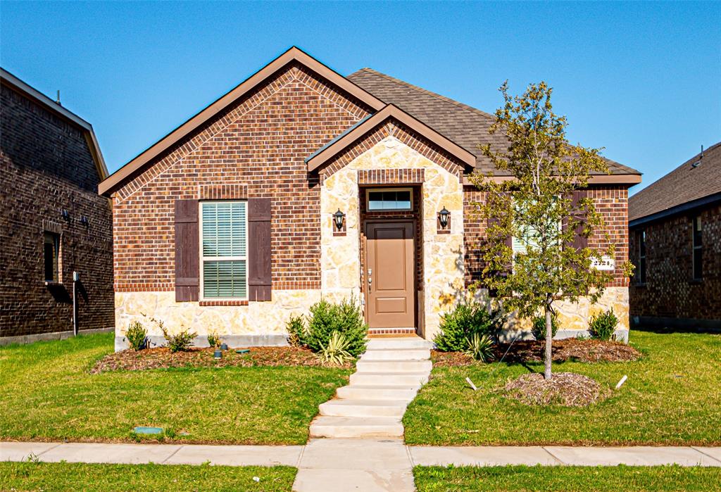 Brick and stone exterior featuring a gabled roofline, decorative window shutters, dual exterior light fixtures, and a concrete pathway leading to the front entry Brick and stone exterior featuring a gabled roofline, decorative window shutters, dual exterior light fixtures, and a concrete pathway leading to the front entry
