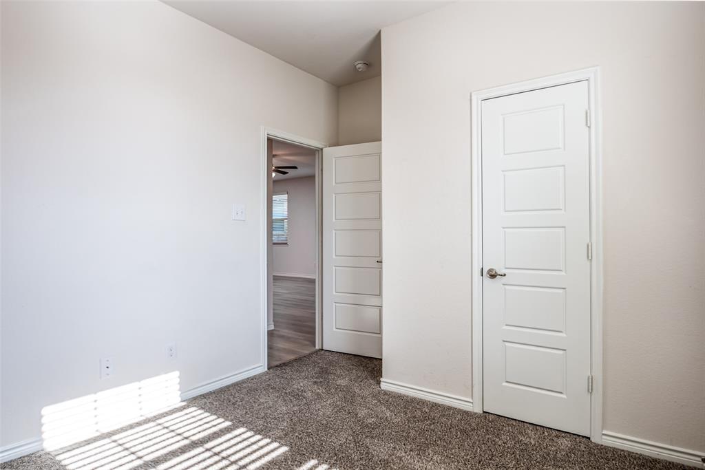 Textured carpeting, white interior doors with contemporary paneling, brushed nickel hardware, light-toned wall finishes, and a ceiling fan in the adjacent space