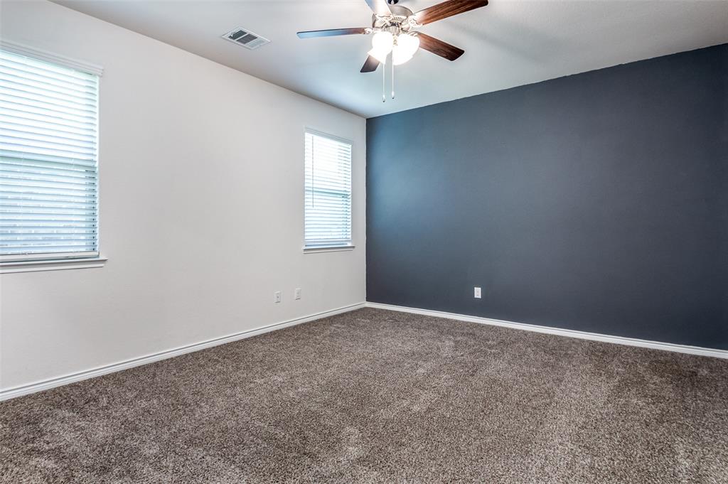 Carpeted flooring, two windows with blinds, ceiling fan with light fixture, white and accent wall finishes