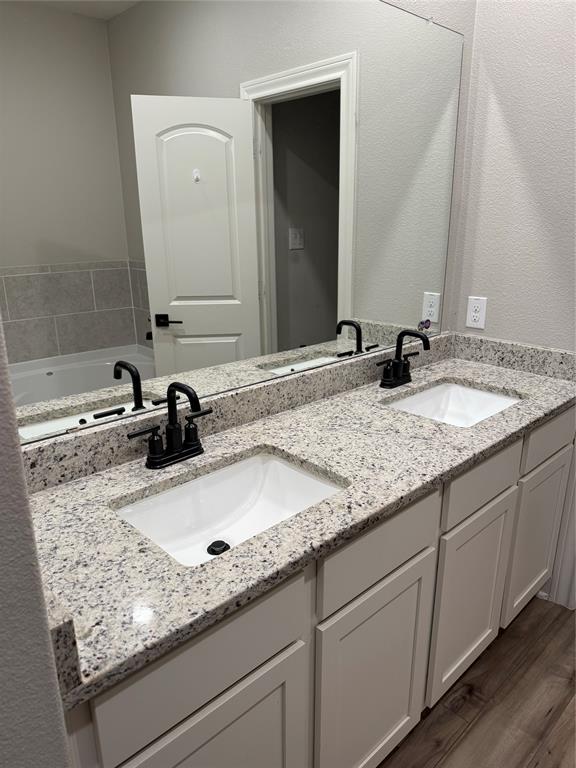 Dual vanity with granite-style countertop, undermount sinks, and matte black fixtures