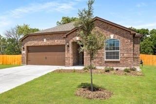 Brick exterior with an arched entry, attached two-car garage, concrete driveway, and established lawn