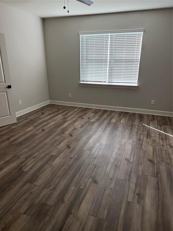 Wood-finish flooring, neutral wall tones, window with horizontal blinds, and a ceiling fan with light fixture