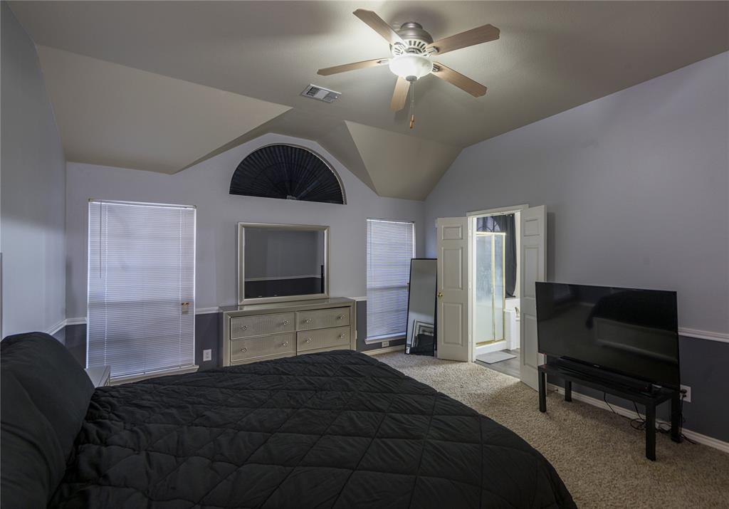 Vaulted ceiling, ceiling fan with light fixture, arched window with blinds, two windows with blinds, carpeted flooring