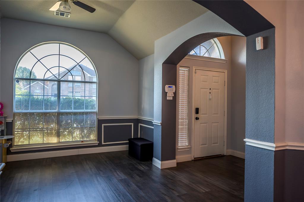 Arched entryway with a transom window, wood-finish flooring, and decorative wall molding Arched entryway with a transom window, wood-finish flooring, and decorative wall molding