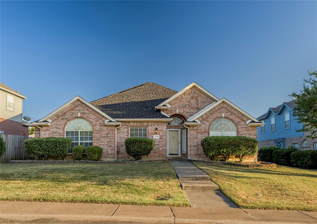 Brick exterior with an arched entry, a pitched roof, and mature shrubbery