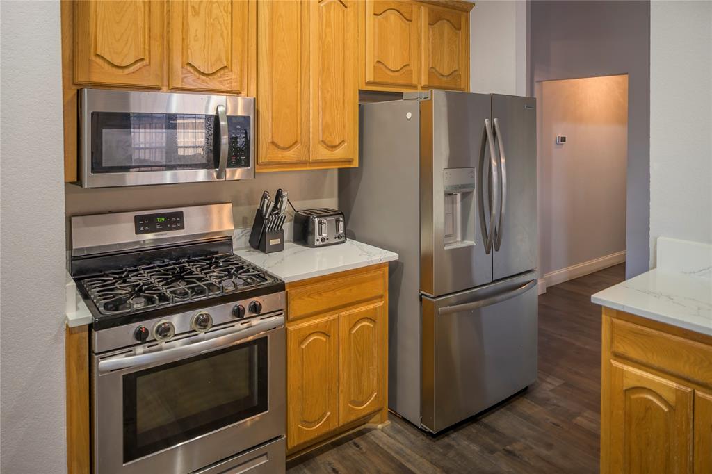 Stainless steel appliances, wood cabinetry, light-toned countertops, and wood-finish flooring Stainless steel appliances, wood cabinetry, light-toned countertops, and wood-finish flooring