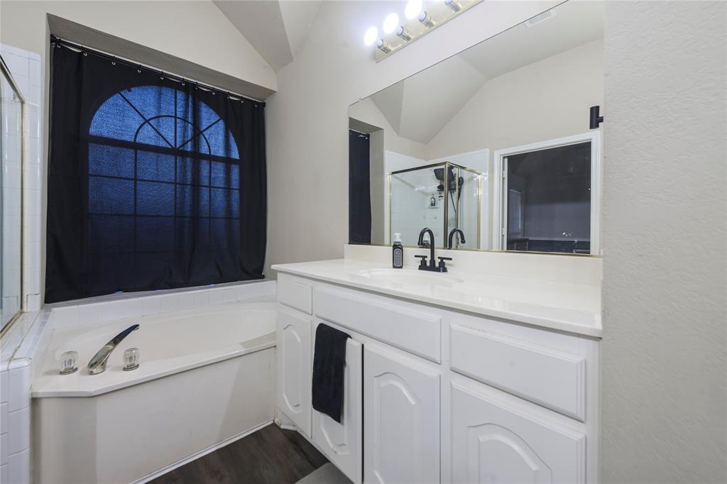 White vanity with a single basin sink, black-finish faucet, and a large mirror