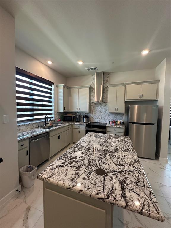 Spacious kitchen featuring an expansive island with a polished countertop, stainless steel appliances, upper and lower cabinetry, recessed lighting, and a coordinating backsplash Spacious kitchen featuring an expansive island with a polished countertop, stainless steel appliances, upper and lower cabinetry, recessed lighting, and a coordinating backsplash