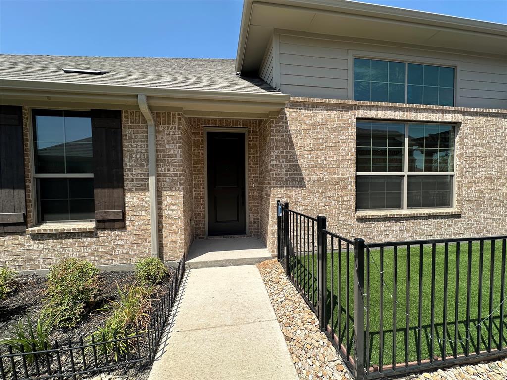 Brick facade with a prominent entry door, dark shutters, multiple windows, and a paved walkway Brick facade with a prominent entry door, dark shutters, multiple windows, and a paved walkway