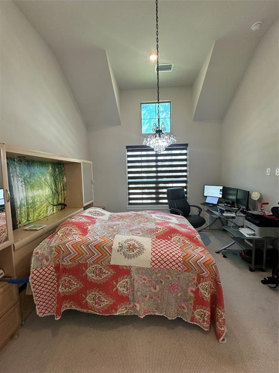 Vaulted ceiling featuring a decorative chandelier, upper transom window, and horizontal window blinds Vaulted ceiling featuring a decorative chandelier, upper transom window, and horizontal window blinds