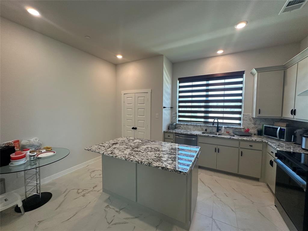 Kitchen featuring an island with stone countertop, stainless steel dishwasher, undermount sink, and recessed lighting Kitchen featuring an island with stone countertop, stainless steel dishwasher, undermount sink, and recessed lighting