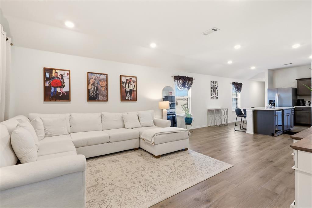 Recessed lighting throughout, wood-finish flooring, ample natural light, kitchen island with counter seating, and stainless steel appliances
